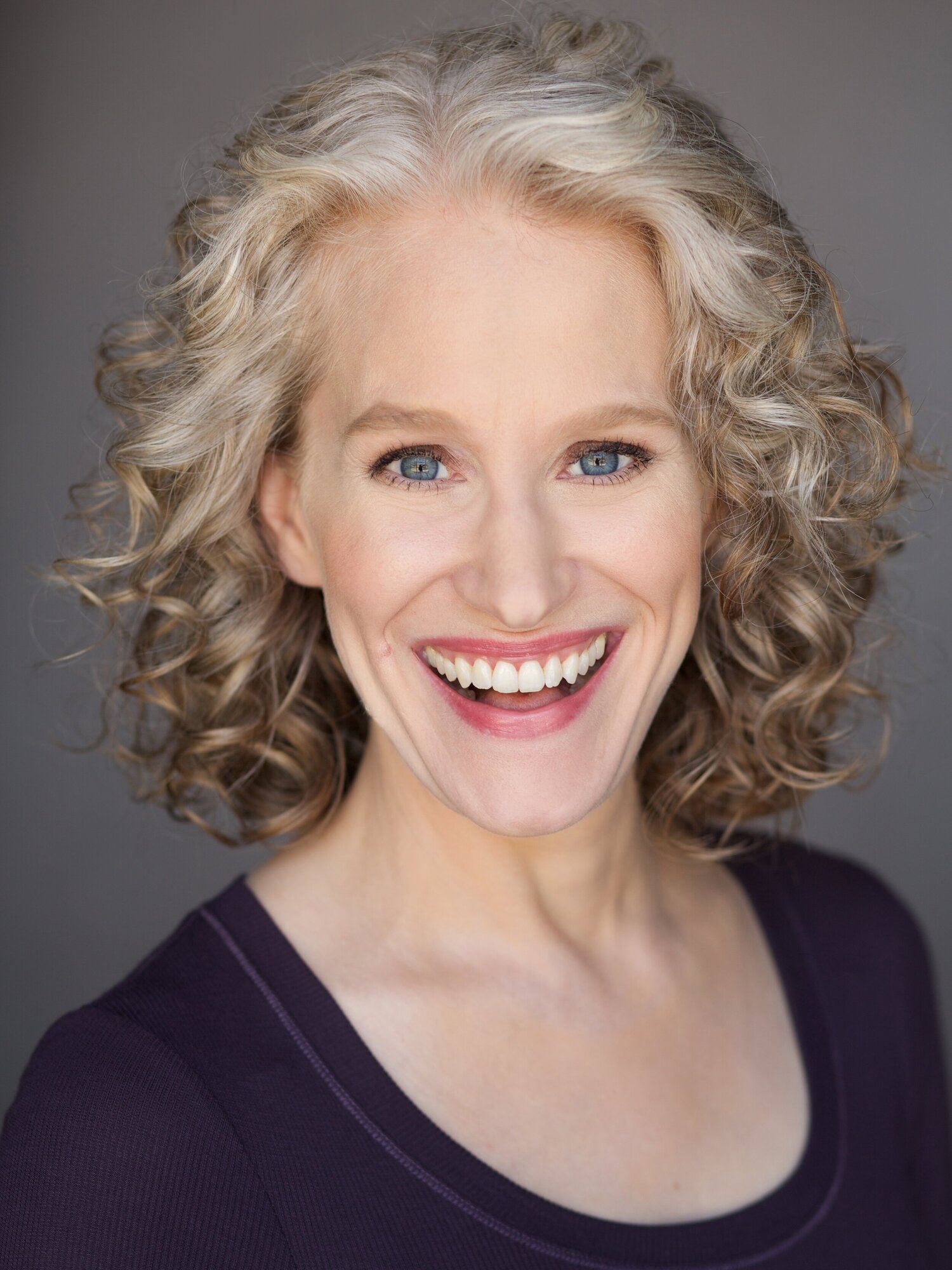 A 3-dimensional image of a book showing a woman in historical clothing and a tartan wrap on her arms standing in the Scottish Highlands. A walking trail is seen behind her disappearing into the mountains. The title of the book is Smoke on the Wind by USA Today bestselling author Kelli Estes.